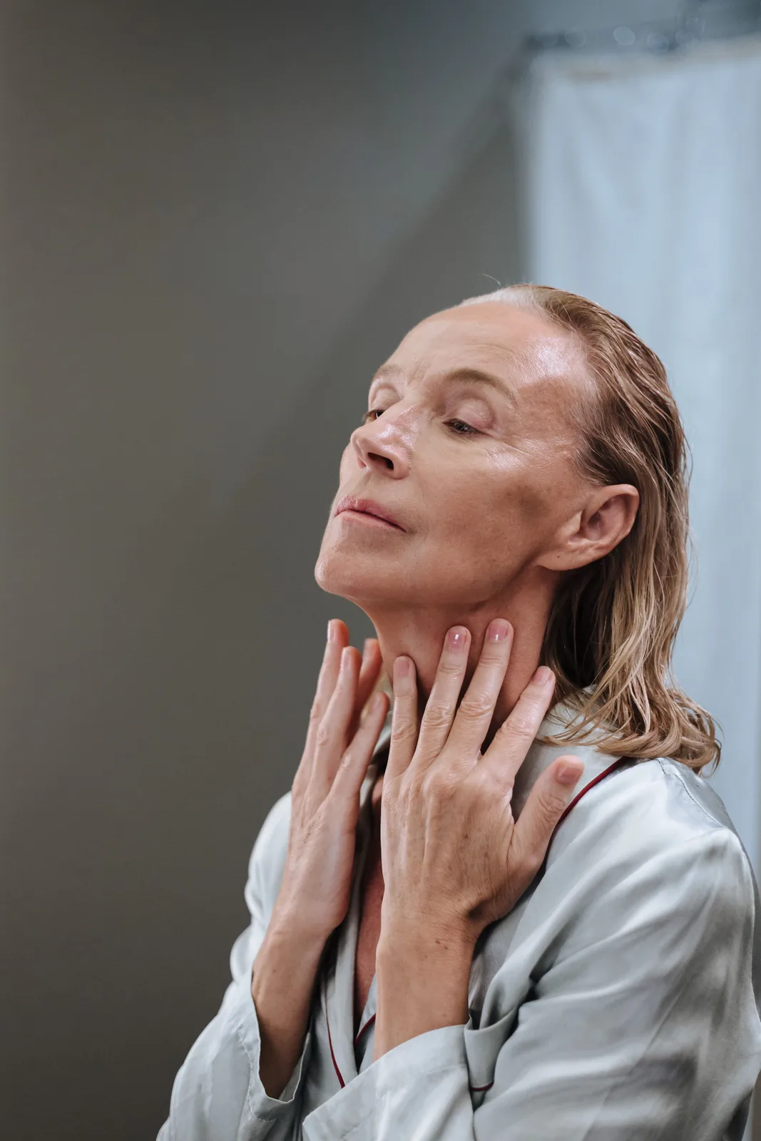 Woman in pyjamas applying cream to her neck. Illustrative stock photograph, not a patient.