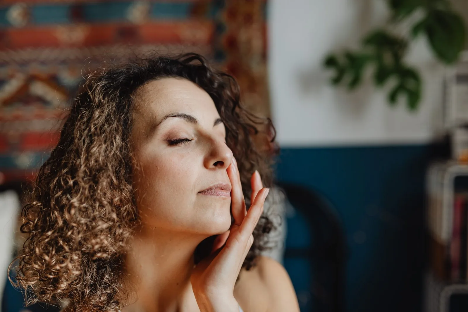 Woman applying cream at home with her eyes closed. Illustrative stock photograph, not a patient.