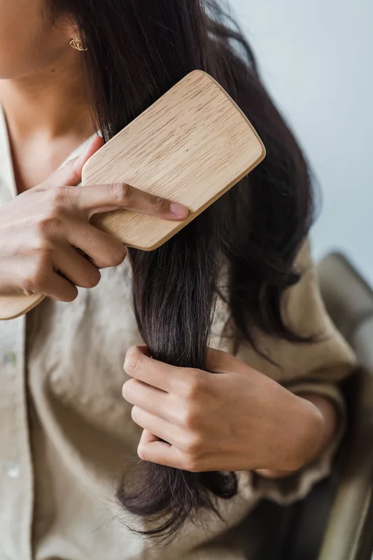 Paddle brush drawn through long dark hair. Illustrative stock photograph, not the product.