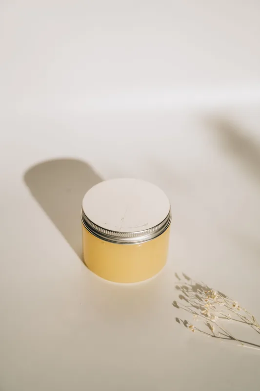 Amber jar with a long shadow on a white surface. Illustrative stock photograph, not the product.