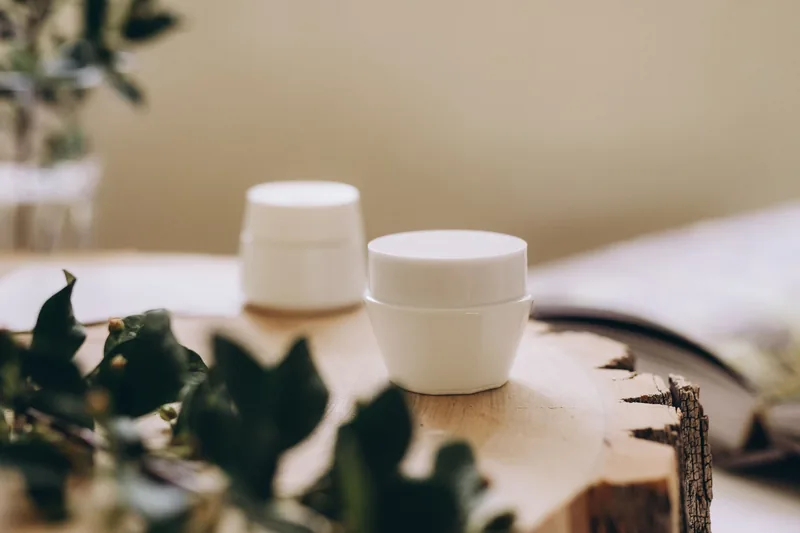 Two white jars on a table with trailing foliage. Illustrative stock photograph, not the product.